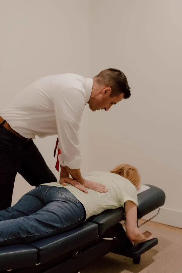 Chiropractor adjusting a patient lying face down on a treatment table during neck pain treatment